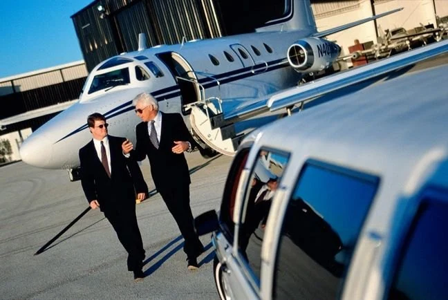 Two executives walking from a private jet to a waiting car